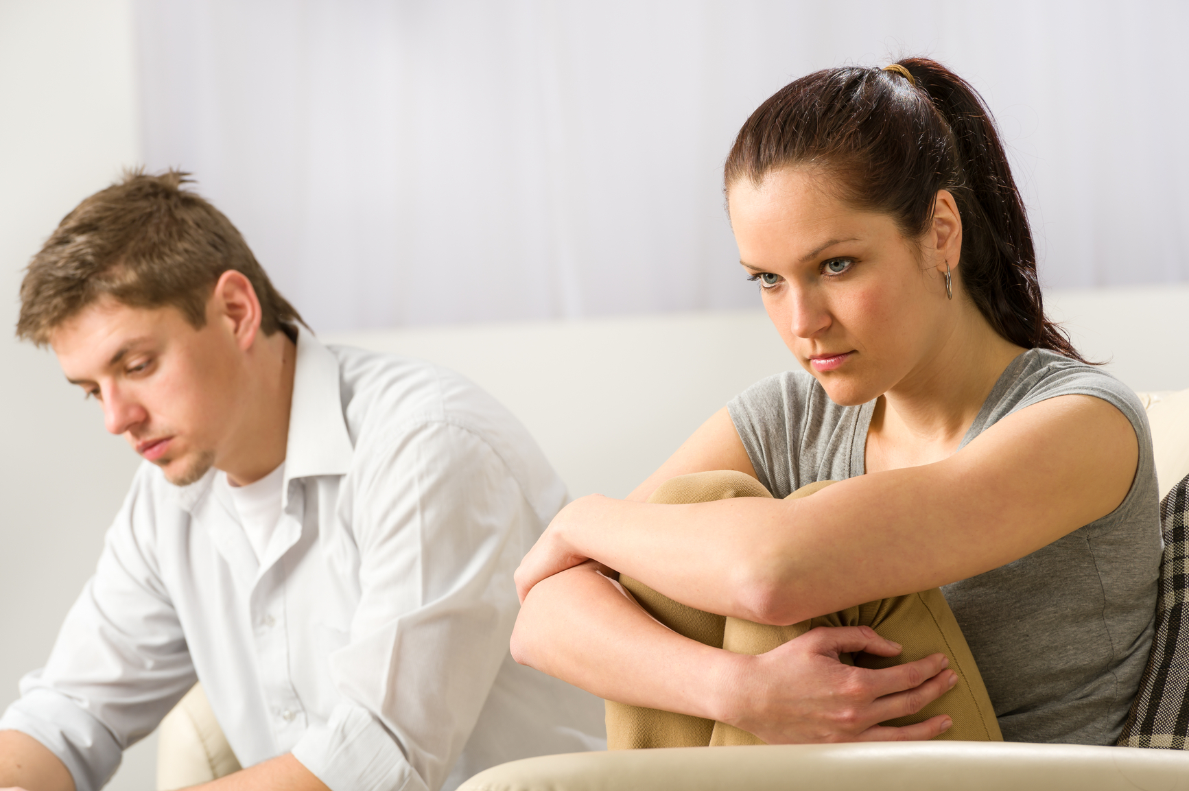 Unhappy couple sitting on couch silently after argument